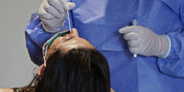 Profissional de saúde coleta amostra nasal de mulher para teste de Covid-19 em um centro de testagem gratuita em Buenos Aires, na Argentina, no dia 10 de janeiro. — Foto: Alejandro Pagni / AFP