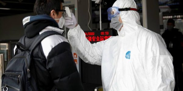 A worker in protective suit uses a thermometer to check the temperature of a man while he enters the Xizhimen subway station, as the country is hit by an outbreak of the new coronavirus, in Beijing, China January 27, 2020. REUTERS/Carlos Garcia Rawlins