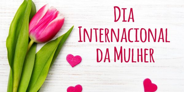 Women's day card with Portuguese words 'dia internacional da mulher'. Tulip flower small hearts on white wooden background.