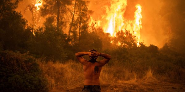 Homem observa um grande incêndio florestal que se aproxima da aldeia de Pefki na ilha de Evia (Eubeia), a segunda maior ilha da Grécia, neste domingo.ANGELOS TZORTZINIS / AFP