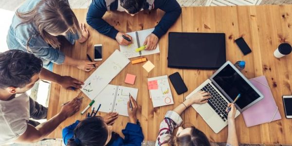 overhead view on young business people around wooden desk