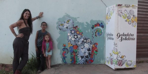 Viviane Mendes faz colagem em parede ao lado da geladeira solidária na Pousada da Esperança
Viviane Mendes, Cristopher Miguel Lima Correia e Ester Cristina Ferraz Lima